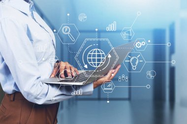 Bulanık ofiste dizüstü bilgisayar kullanan tanınmayan genç bir kadının yan görüntüsü. Bulutlu bir bilgisayar arayüzü var. Tonu ayarlanmış resim