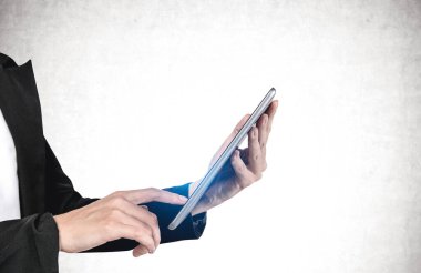 Beton duvarın yanında tablet bilgisayar kullanan tanınmayan genç bir iş kadını portresi. İletişim ve teknoloji kavramı