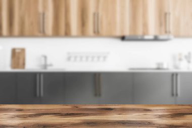 Ürününüz için ahşap masa bulanık modern mutfakta beyaz tuğla duvarlar, beton zemin, ahşap dolaplar ve gri dolaplar. 3D oluşturma maketi