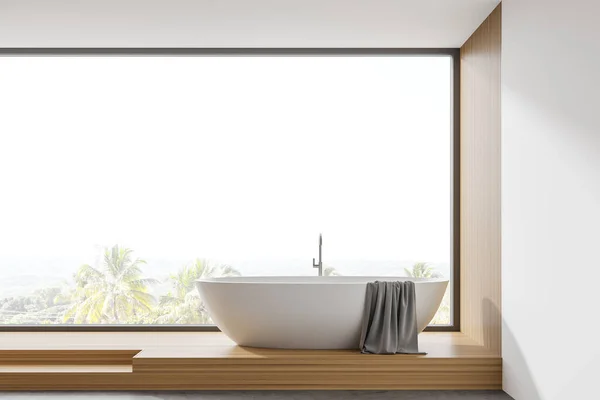 Interior of modern panoramic bathroom with white and wooden walls, stairs and comfortable bathtub standing near window with blurry tropical view. 3d rendering