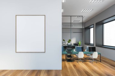 Gri duvarları, ahşap zemini, beyaz sandalyeli mavi bilgisayar masaları ve bulanık şehir manzaralı pencereleri olan modern açık uzay ofisinde asılı poster çerçevesi dikey. 3d oluşturma