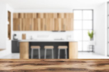 Ürününüz için ahşap masa bulanık modern mutfakta beyaz tuğla duvarlar, ahşap dolaplar tabureler ve gri dolaplarla dolu bir bar. Merdivenler. 3D oluşturma maketi