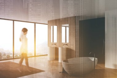 Beyaz ve ahşap duvarları, çift lavabosu ve rahat küveti olan panoramik banyoda yürüyen bulanık genç bir kadın. Renkli resim çift pozlama