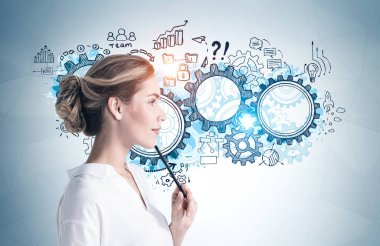 Üzerinde iş stratejisi çizimi olan gri duvarın yanında duran düşünceli genç iş kadını. Planlama kavramı