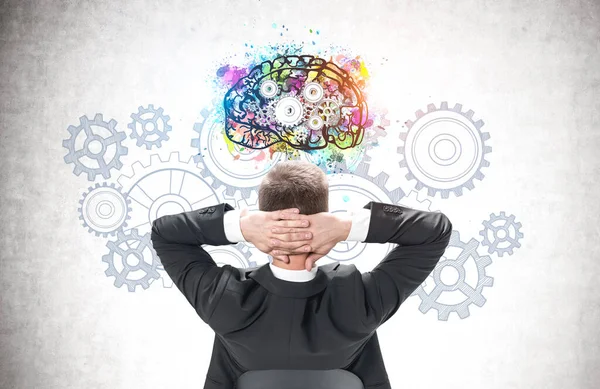壁に描かれたカラフルな脳のスケッチを見て自信に満ちた若いビジネスマンの背面図 — ストック写真