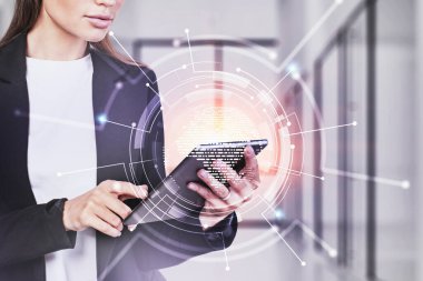 Tanımlanamayan genç iş kadını bulanık ofiste tablet kullanıyor ve ağ arayüzü iki katına çıkıyor. Tonu ayarlanmış resim