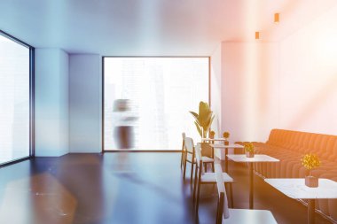 Beyaz duvarları, beton zemini, siyah kanepesi ve yuvarlak masalarıyla modern restoranda yürüyen bulanık genç bir kadın. Tonu ayarlanmış resim