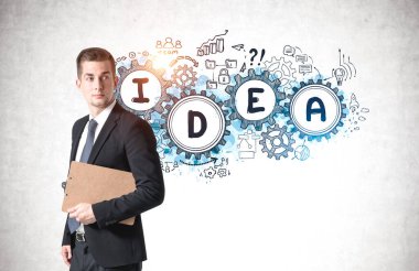 Üzerinde renkli çizimler olan beton duvarın yanında duran genç ve ciddi bir iş adamı.