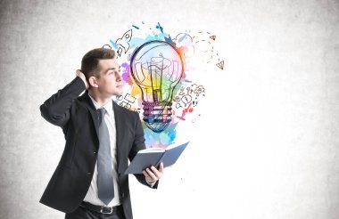 Beton duvara çizilmiş yaratıcı iş fikri skecine bakan kafası karışmış genç iş adamının yan görüntüsü. Model