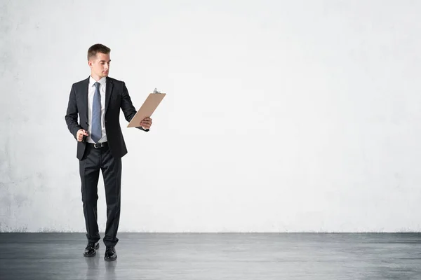 Full Length Portrait Young Businessman Clipboard Standing Concrete Room Concept — Stock Photo, Image