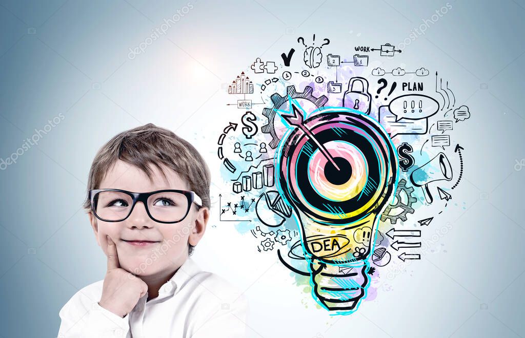 Smiling little boy in glasses standing near blue wall with colorful business goal sketch drawn on it