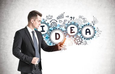 Akıllı telefonlu genç Avrupalı işadamının, yaratıcı fikir çizimiyle beton duvarın yanında duruşu.