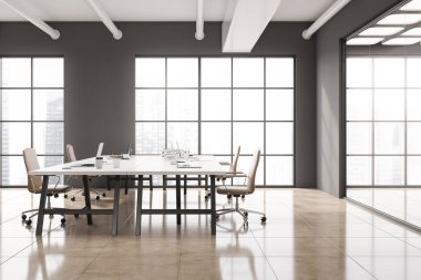 Gri duvarları, beton zemini ve uzun beyaz bilgisayar tabloları olan şık bir açık uzay ofisi. 3d oluşturma