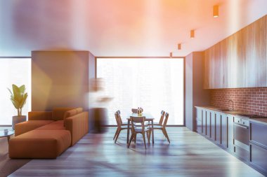 Mutfakta gri duvarları, ahşap zemini ve yanında kanepe olan oturma odası olan bulanık genç bir kadın. Tonu ayarlanmış resim