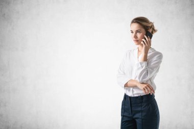 Beton duvarın yanında akıllı telefondan konuşan Avrupalı genç iş kadınının portresi. İletişim kavramı. Model