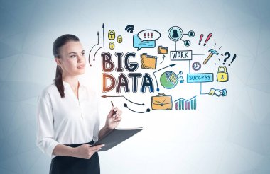 Üzerinde renkli büyük veri çizimi olan gri duvarın yanında duran defterli genç bir iş kadını.