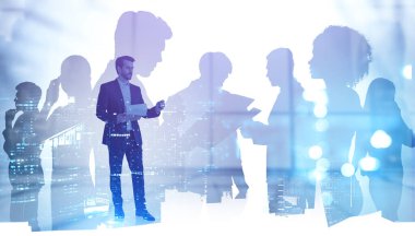 Tanımlanamayan işadamı, bulanık ofiste tabletle çalışıyor ve ekibini iki kez gösteriyor. Tonu ayarlanmış resim