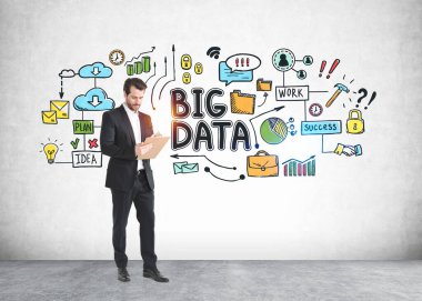 Sakallı genç işadamı, üzerinde renkli büyük bir veri çizimi olan beton duvarın yanında duruyor.