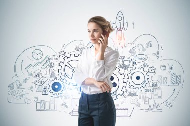 Beton duvarın yanında akıllı telefondan konuşan genç bir iş kadını..