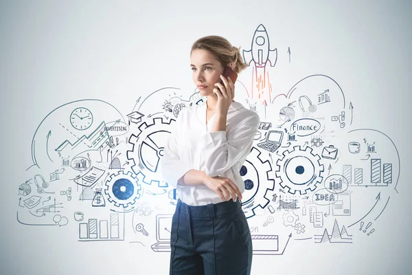 Beton duvarın yanında akıllı telefondan konuşan genç bir iş kadını..