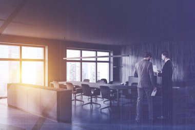 Gri toplantı odasında uzun konferans masası olan iki iş adamı. Renkli resim çift pozlama