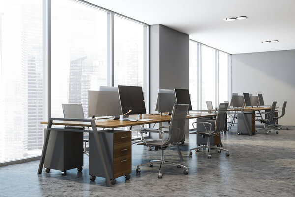 Уголок стильного открытого пространства офиса с серыми стенами, бетонным полом и рядами компьютерных столов. 3d-рендеринг
