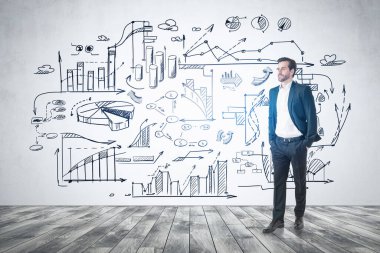 Kendine güvenen genç işadamı beton odada duvarında bir iş çizimiyle dikiliyor..