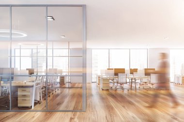 Bulanık genç iş adamı beyaz duvarları ve sıra sıra bilgisayar masalarıyla modern ofis binasında yürüyor. Tonu ayarlanmış resim