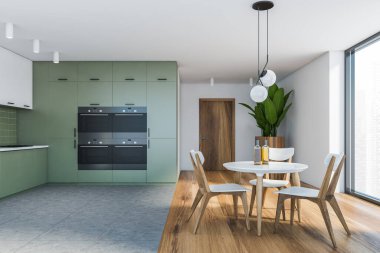 Beyaz ve yeşil duvarlı şık mutfak manzarası, döşeme döşemesi, eşyalar halinde yapılmış yeşil dolaplar ve sandalyeli yuvarlak yemek masası. 3d oluşturma