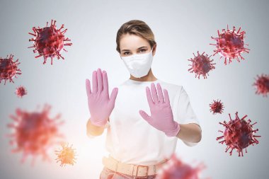 Koruyucu maskeli ve lastik eldivenli genç bir iş kadını kırmızı koronavirüsle beton arka planda duran dur işaretini gösteriyor. Tonu ayarlanmış resim