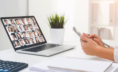 Dahili ofisteki iş arkadaşlarıyla yaptığı görüntülü konuşma sırasında akıllı telefon kullanan genç iş kadınının yan görüntüsü.