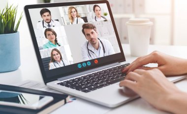 Tıp doktorlarıyla görüntülü görüşme yapan ve dizüstü bilgisayar kullanan tanınmamış genç bir kadının elleri. Teknoloji ve teletıp kavramı