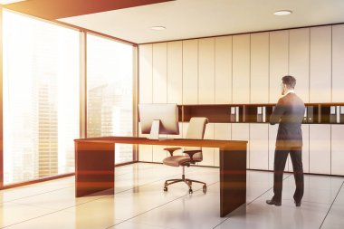 Modern CEO ofisinde beyaz duvarları, döşemeleri ve bilgisayar masası olan genç bir işadamı. Yönetim kavramı. Tonu ayarlanmış resim