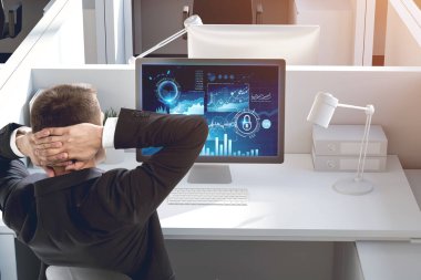 Modern ofisteki bilgisayar ekranındaki grafiklere bakan genç işadamının arka görünüşü. Yatırım ve başarı kavramı. Tonu ayarlanmış resim