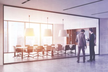 Beyaz ve ahşap duvarları, beton zemini ve uzun konferans masası olan modern toplantı odasının yakınında konuşan genç işadamları. Renkli resim çift pozlama