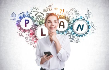 Zeki telefonlu neşeli genç bir kadın beton duvarın yanında duruyor ve üzerine renkli bir iş planı çizimi yapılmış.