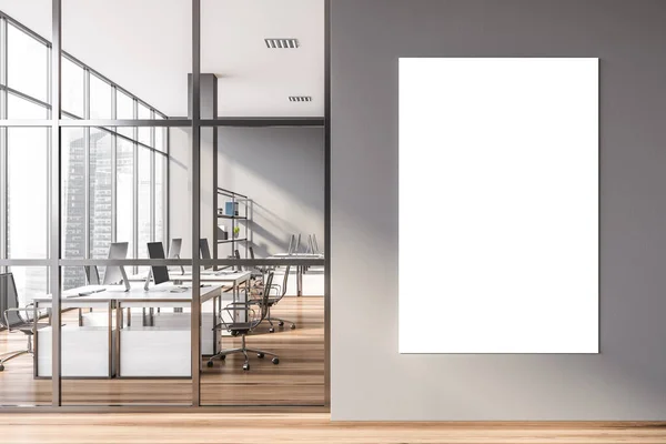 Mock up poster hanging in modern open space office with gray walls, wooden floor and rows of white computer tables. 3d rendering