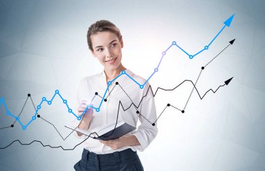 Üzerinde grafikler olan gri duvarın yanında duran neşeli genç iş kadını. Yatırım ve başarı kavramı