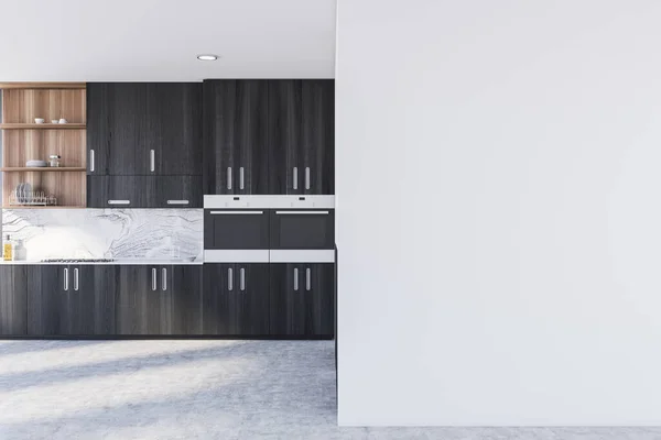 Interior of stylish kitchen with white walls, concrete floor and black cabinets with built in sink and cooker. Mock up wall to the right. 3d rendering