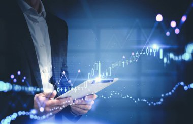 Bulanık panoramik ofisteki tabletle işadamının elini kapat ve iki kat mali grafikle donat. Tonu ayarlanmış resim