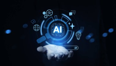 Fütürist simgelerle parlayan bir yapay zeka arayüzü, karanlık bir arka planda açık bir elin üzerinde görünür. Bu da yapay zeka teknolojisini temsil eder.