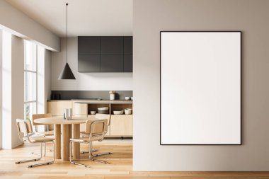 Ahşap masa ve sandalyeli modern yemek odası arka planda asgari mutfak, bej duvarda büyük dikey boş poster. 3B Hazırlama