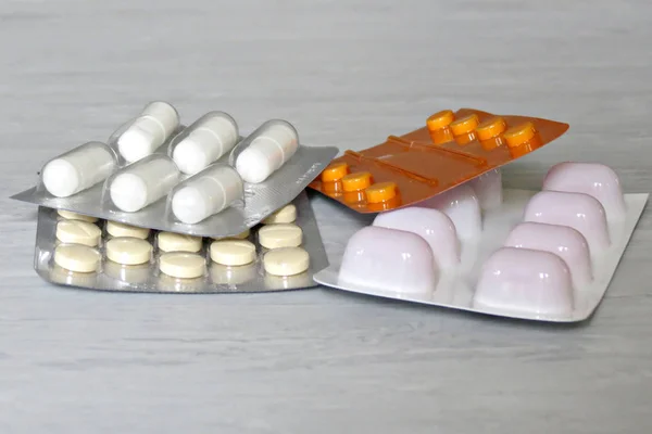 Pilulky na léky v krabích prášků v puchýři a prášky zabalené v puchýřkách-bílé, Yelow, červené. Šedé pozadí — Stock fotografie