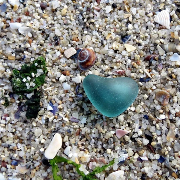 Teal corazón de cristal de mar en la playa. Peinando la playa en la orilla del mar. Paseo de playa . — Foto de Stock
