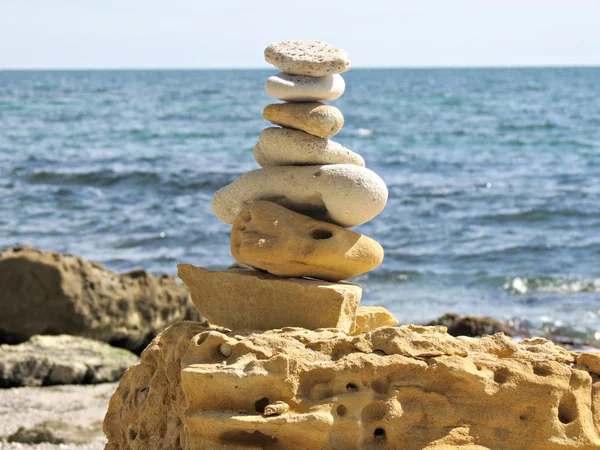 Simple pila de guijarros aplomo, escultura zen roca, una torre de piedra. Playa de piedra de arena zen cairn. Una pirámide de piedra en la orilla del mar . — Foto de Stock