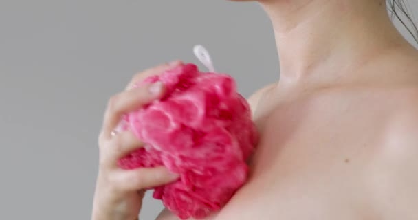 Woman takes bath rubbing shoulders and chest with foam using loofah, side view. — Stock Video