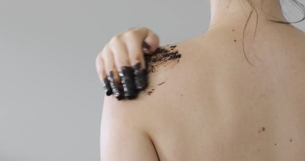 Mujer aplicar exfoliante de café natural orgánico negro en el hombro, vista posterior de primer plano . — Vídeos de Stock