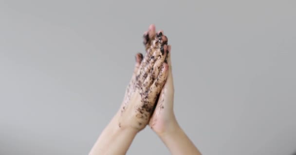 Жінка стискає руки органічний кавовий скраб на сірому фоні, вид крупним планом . — стокове відео