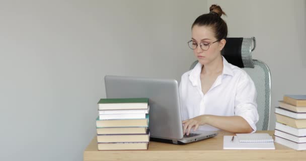 Chica estudiante universitaria que estudia en el ordenador portátil escribir notas en cuaderno en la mesa . — Vídeo de stock