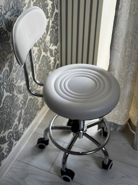 Modern white swivel stool with chrome legs and wheels in a stylish interior.